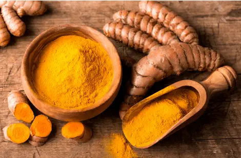 turmeric root vegetable and a bowl of turmeric powder