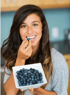 woman eating blueberries and smiling